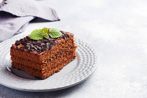 A piece of truffle cake with chocolate on a gray concrete background. Copy space - Foto, afbeelding