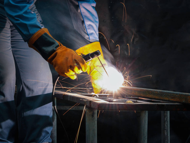 Teollisuuden työntekijä yllään turvanaamio, kypärä, ja turvallinen lasit hitsaus metalli rakentaminen tehtaalla. Teollinen mekaanikko insinööri työskentelee tehtaalla hitsaus teräsrakenne - Valokuva, kuva