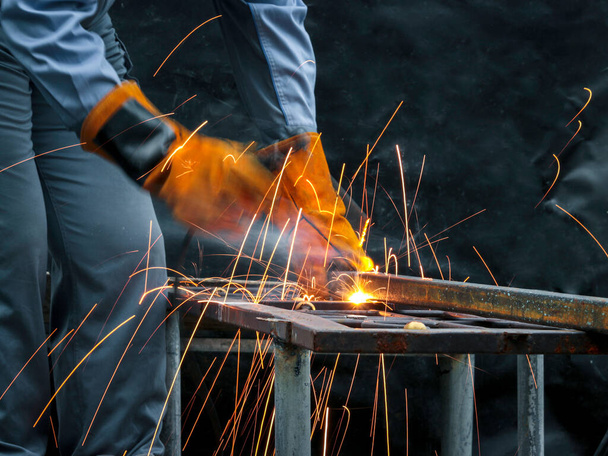 Teollisuuden työntekijä yllään turvanaamio, kypärä, ja turvallinen lasit hitsaus metalli rakentaminen tehtaalla. Teollinen mekaanikko insinööri työskentelee tehtaalla hitsaus teräsrakenne - Valokuva, kuva