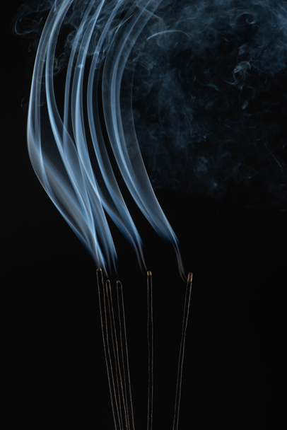 палаючі палички аромату з димом на чорному фоні
 - Фото, зображення