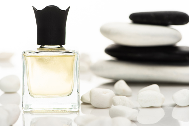 вибірковий фокус домашніх парфумів у пляшці біля спа-камінців на білому тлі
 - Фото, зображення