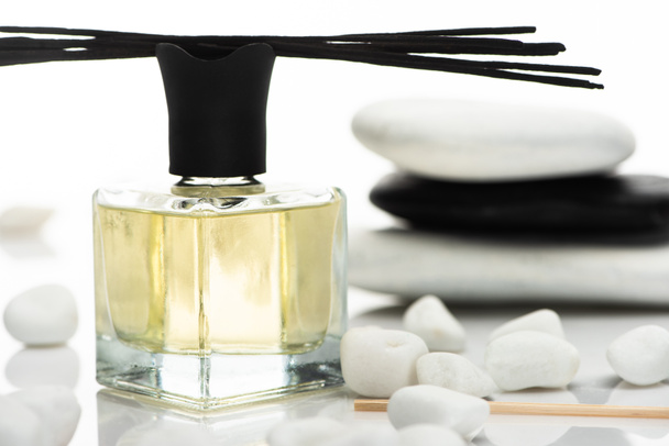 selektivní zaměření vonných tyčinek a parfémů v blízkosti lázeňských kamenů izolovaných na bílém - Fotografie, Obrázek