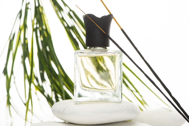 selektiver Fokus von Aromastäbchen in der Nähe von Parfüm in der Flasche auf Wellness-Stein auf weißem Hintergrund - Foto, Bild