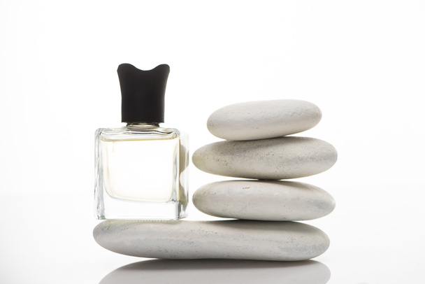 perfume casero en botella cerca de piedras de spa sobre fondo blanco
 - Foto, Imagen
