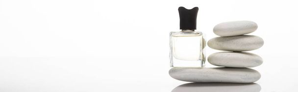 perfume casero en botella cerca de piedras de spa sobre fondo blanco, plano panorámico
 - Foto, imagen