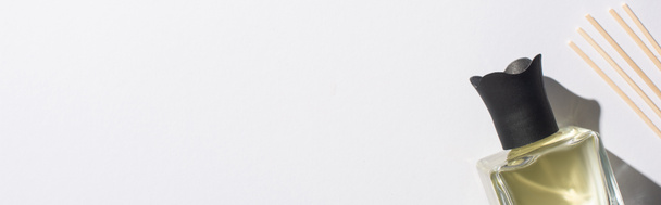 vista superior de varas de aroma com perfume em garrafa no fundo branco, tiro panorâmico
 - Foto, Imagem