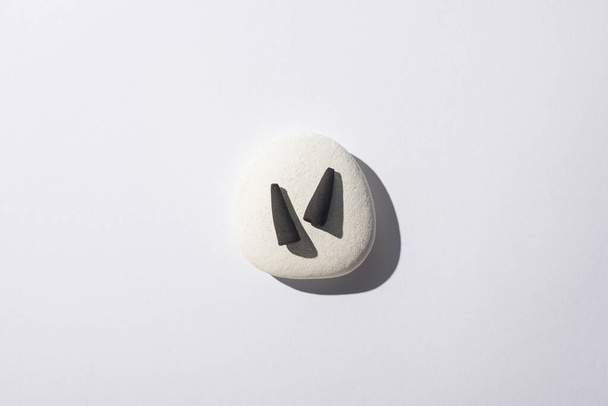 widok z góry czarne szyszki kadzidła na kamień spa na białym tle - Zdjęcie, obraz