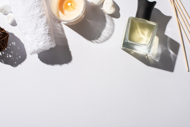 Draufsicht auf Duftstäbchen mit Parfüm in der Flasche in der Nähe von Baumwolltuch, Steinen und Kerze auf weißem Hintergrund - Foto, Bild