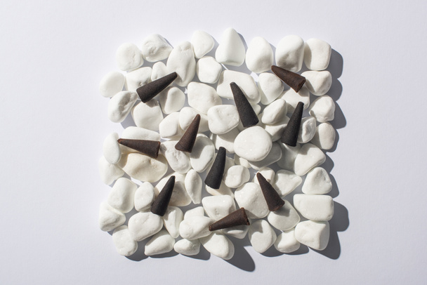 vista superior de cones de incenso em quadrado feito de pedras sobre fundo branco
 - Foto, Imagem