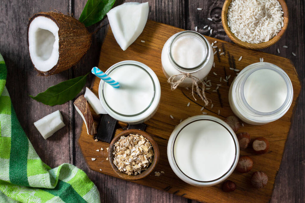 Gezond veganistisch voedselconcept. Assortiment biologische veganistische melk van kokos, noten, havermout, rijst op een keukentafel. Bovenaanzicht platte lay achtergrond. - Foto, afbeelding