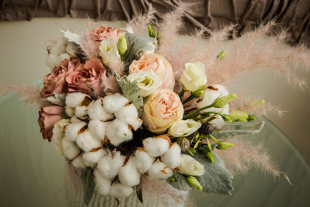 κοντινό πρωτότυπο μπουκέτο από λευκά χνουδωτά βαμβακερά λουλούδια, διάφορα τριαντάφυλλα και διάφορες διακοσμητικές λεπτομέρειες - Φωτογραφία, εικόνα