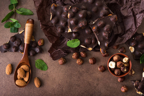 sabrosas barras de chocolate con nueces, menta fresca y almendras sobre un fondo de piedra. Comida dulce, vista superior
 - Foto, Imagen