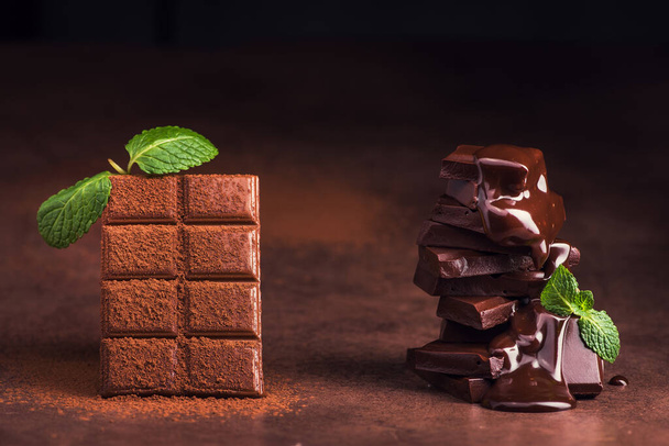 melted chocolate pouring into a piece of chocolate bars with green mint leaf on a table - Foto, Imagem