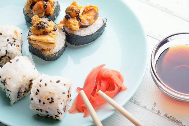 Rolos de sushi em prato azul, pauzinhos e molho de soja - Foto, Imagem