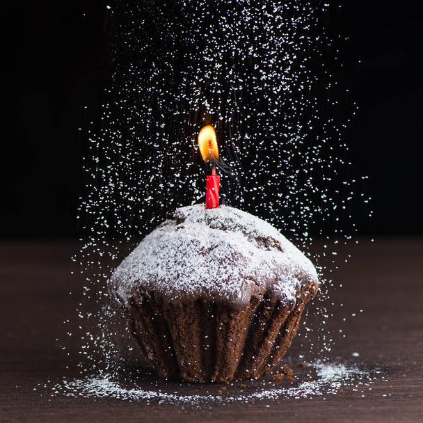 jälkiruoka suklaakakku syntymäpäivä yhdellä punaisella kynttilällä, lentojauhe mustalla taustalla - Valokuva, kuva