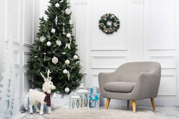 White Christmas room with Christmas tree, decorative deer and armchair. Beautiful interior - Zdjęcie, obraz
