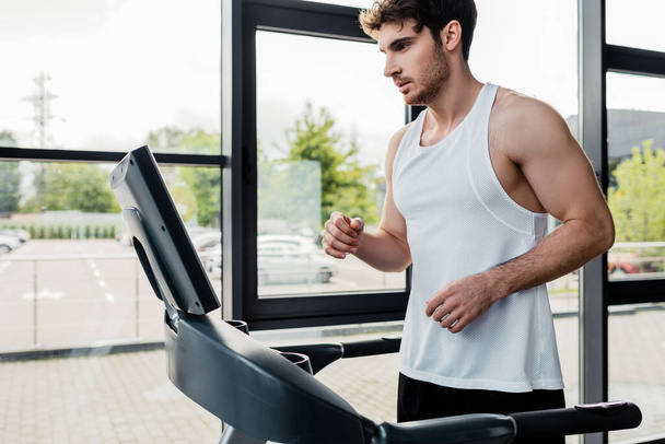 handsome sportsman looking at screen on modern treadmill  - Fotó, kép