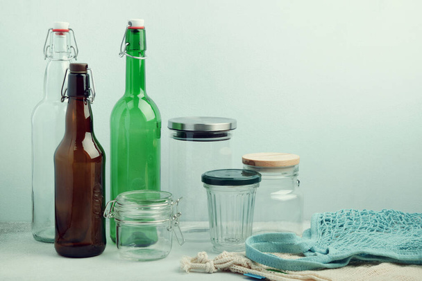 Эко-пакеты, многоразовые стеклянные бутылки и банки на столе. Устойчивый образ жизни. Концепция покупки и хранения нулевых отходов
 - Фото, изображение