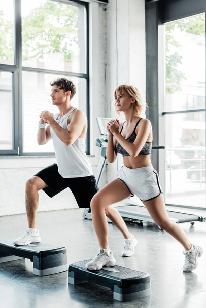 sport couple with clenched hands doing lunges exercising on step platforms  - Foto, Imagem
