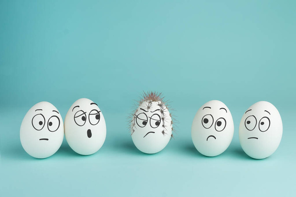 Mau conceito de personagem. Ovo espinhoso. Cinco ovos brancos com rostos desenhados em um fundo azul
. - Foto, Imagem