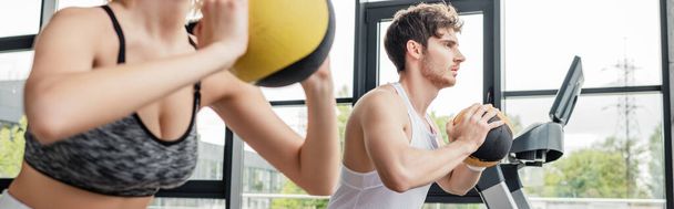 panoramic crop of sportswoman and sportsman exercising with balls in gym  - Fotó, kép