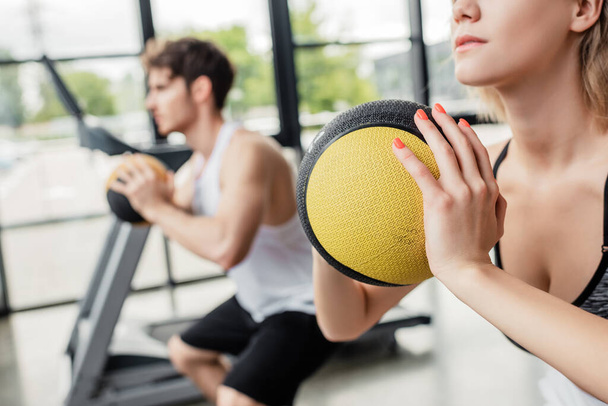 selective focus of young sportswoman exercising with ball near sportive man  - Photo, Image