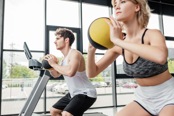 selective focus of handsome and sportive man exercising with ball near girl  - Photo, Image