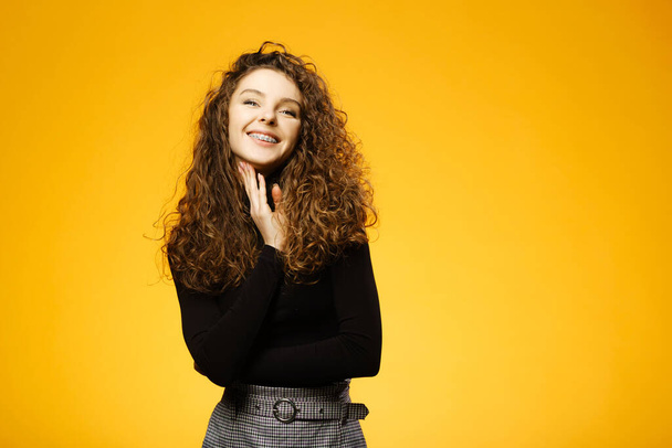 Pretty girl with curly hair isolated on yellow background - Photo, Image