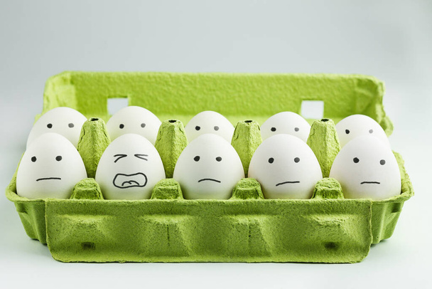 Huevos con caras dibujadas en la caja de huevos. Concepto de agotamiento, estrés en el trabajo
. - Foto, Imagen