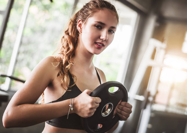 Cinematic tone of young attractive fitness woman exercise with machine and dumbbell in gym. Individual sport to fit muscles of body for healthy life concept. - Photo, Image