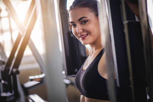 Cinematic tone of young attractive fitness woman exercise with machine in gym. Individual sport to fit muscles of body for healthy life concept.  - Photo, Image