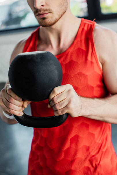 cropped view of strong man exercising with heavy dumbbell in sports center  - Photo, Image