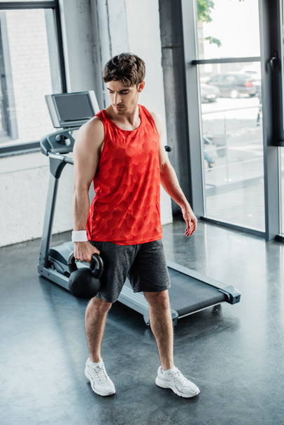 strong man holding heavy dumbbell near treadmill in sports center  - Foto, Imagem