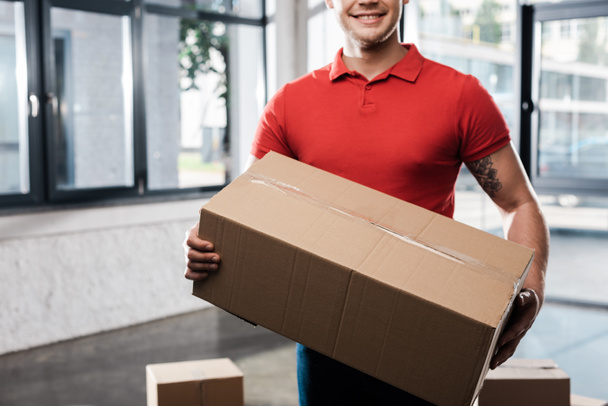 cropped view of positive delivery man holding carton box - Photo, Image