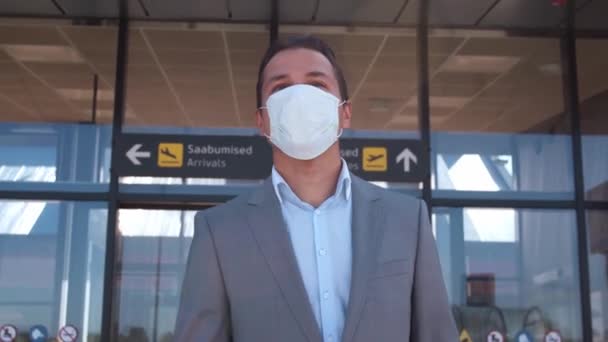 Elegant businessman wearing protective mask in airport. Young mail entrepreneur in formalwear. Pandemic, new rules of control, business trip and traveling concepts. - Felvétel, videó