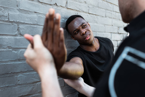 foyer sélectif de l'homme afro-américain blessé regardant policier toucher la main, concept de racisme  - Photo, image