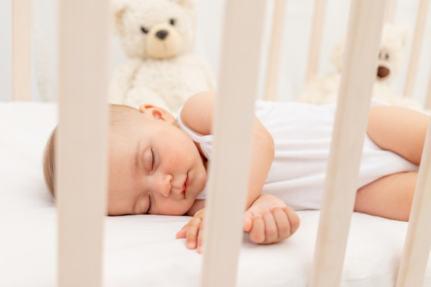 Mała dziewczynka 6 miesięcy śpi w białym łóżku, zdrowy sen dziecka - Zdjęcie, obraz