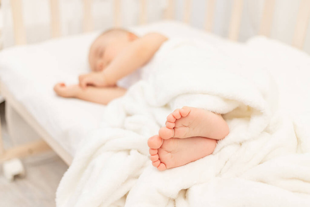 jambes de bébé en bref sur le fond d'un bébé endormi dans un lit blanc, un sommeil sain et calme de bébé - Photo, image