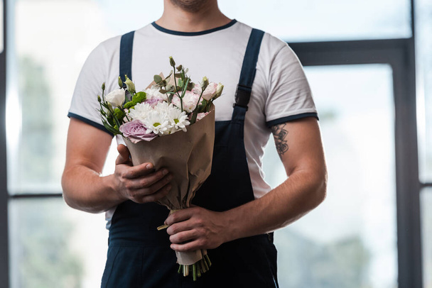 przycięte widok dostawca człowiek gospodarstwa bukiet kwitnących kwiatów  - Zdjęcie, obraz