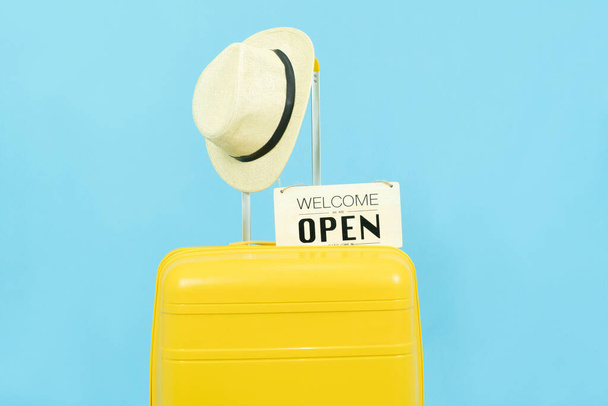 Summer holidays, vacation and travel concept.Yellow Suitcase or luggage bag with sun hat on blue background for copy space. - Fotografie, Obrázek