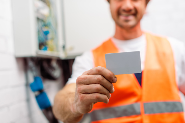 Selective focus of electrician in safety vest holding empty card  - Photo, Image