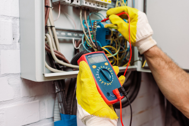 Cropped view of workman in gloves using multimeter while checking voltage of electric panel - Zdjęcie, obraz