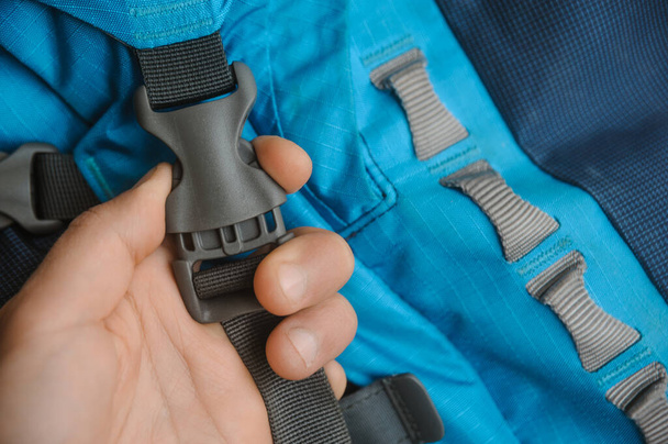 grey fastex buckle of blue trekking backpack opened by man hand - Zdjęcie, obraz