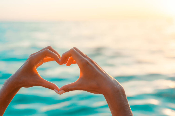 woman Hands in heart shape at blue sea background. ocean love - Zdjęcie, obraz