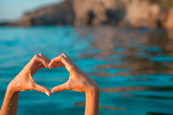 Sea love. Hands in heart shape at blue sea background. Copy space - Fotó, kép