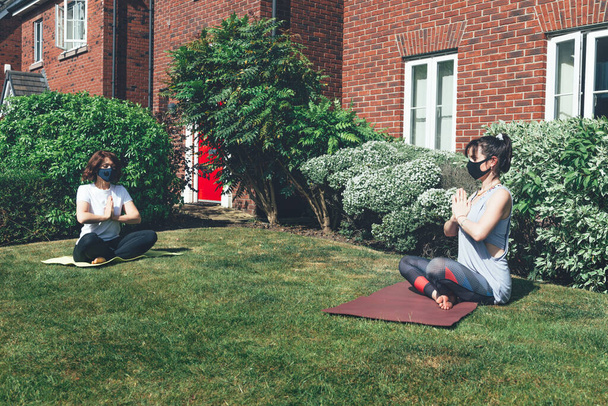 Treinamento de ioga no jardim com distância social
 - Foto, Imagem