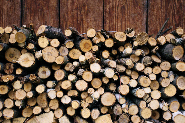 壁には薪が均等に積み重ねられています。乾燥した木の丸太。美しい食感. - 写真・画像