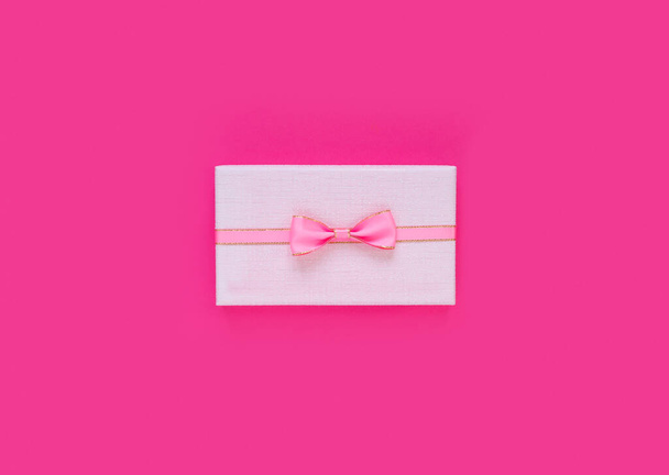 Pink gift box with bow and ribbon on paper background with empty place for text. Copy space for text. Flat lay, top view concept. - Fotó, kép