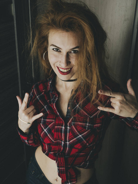 Lány bozontos vicces frizura mosolyog, és azt mutatja, gesztus rock - Fotó, kép