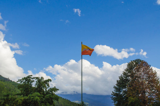Le battement du drapeau national du Bhoutan dans la douce brise dans les genoux des montagnes et de la vallée en face de Thimphu Dzong - Photo, image